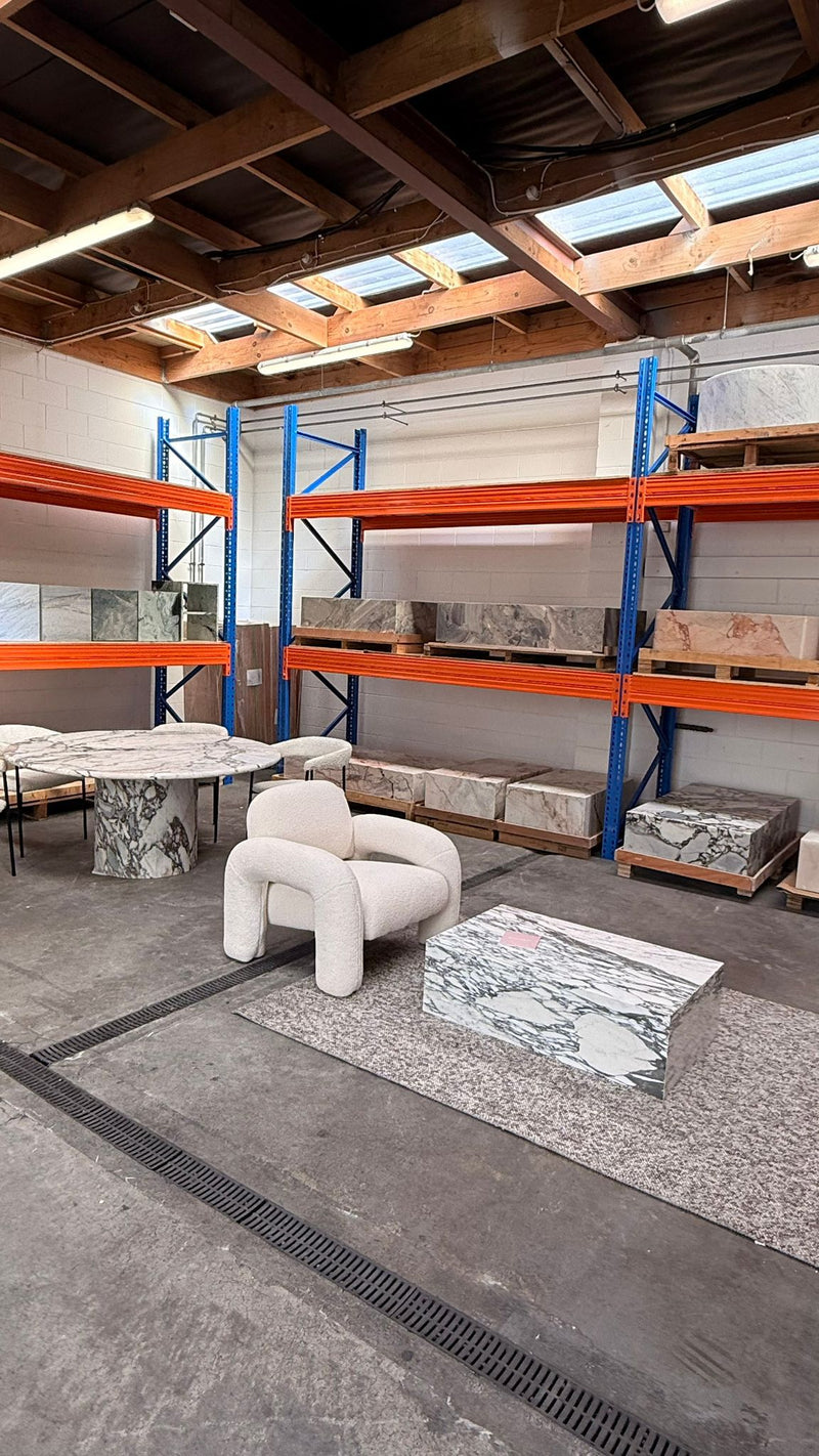 Natural Stone Co. showroom displaying marble tables, stone furniture and curated décor pieces available by appointment.